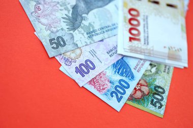 Arjantin pezosu büyük miktarlarda para kırmızı renkli masaya yakın duruyor. Finans ve bankacılık kavramı