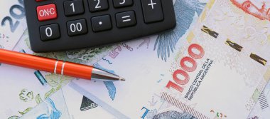 Arjantin Pezosu 'nun büyük miktarlarda para banknotları kalem ve hesap makinesiyle masanın üzerinde duruyor. Maliye ve vergi ödeme kavramı
