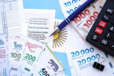 Arjantin Pezosu 'nun para faturaları kalem, hesap makinesi, pasaport ve vergi formlarıyla dolu. Finans ve bankacılık kavramı