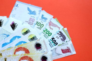 Arjantin pezosu büyük miktarlarda para kırmızı renkli masaya yakın duruyor. Finans ve bankacılık kavramı