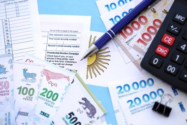 Arjantin Pezosu 'nun para faturaları kalem, hesap makinesi, pasaport ve vergi formlarıyla dolu. Finans ve bankacılık kavramı