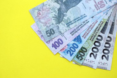 Arjantin pezosu büyük miktarlarda banknotlar sarı renkli masaya yakın duruyor. Finans ve bankacılık kavramı