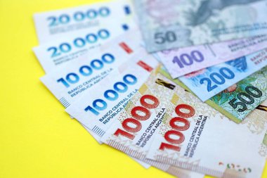 Arjantin pezosu büyük miktarlarda banknotlar sarı renkli masaya yakın duruyor. Finans ve bankacılık kavramı