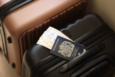 Biletli İngiliz pasaportu havaalanı bekleme salonundaki turistik bavulun üzerinde yatıyor. Dünya çapında seyahat ve uluslararası turizm kavramı