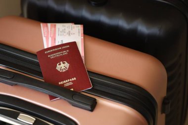 Biletli Almanya pasaportu havaalanındaki bekleme salonunda duran turistik bavulun üzerinde yatıyor. Dünya çapında seyahat ve uluslararası turizm kavramı