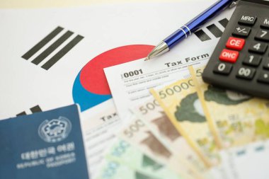 Güney Kore büyük miktarda para kazandı. Masada kalem, hesap makinesi, pasaport ve vergi formları var. Vergi ödeme ve muhasebe kavramı