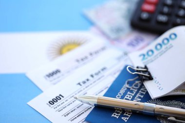 Arjantin Pezosu 'nun para faturaları kalem, hesap makinesi, pasaport ve vergi formlarıyla dolu. Finans ve bankacılık kavramı