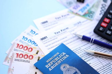Arjantin Pezosu 'nun para faturaları kalem, hesap makinesi, pasaport ve vergi formlarıyla dolu. Finans ve bankacılık kavramı