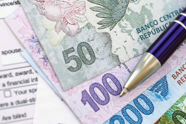 Arjantin pezosu. Büyük miktarda para. Masada, kalem ve vergi formları var.