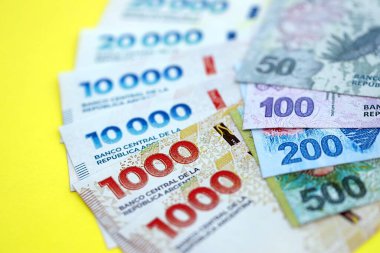 Arjantin pezosu büyük miktarlarda banknotlar sarı renkli masaya yakın duruyor. Finans ve bankacılık kavramı