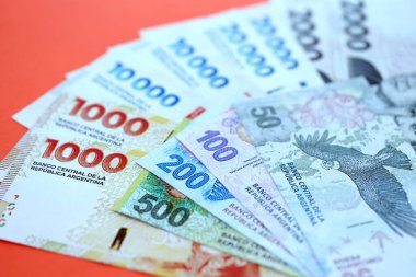 Arjantin pezosu büyük miktarlarda para kırmızı renkli masaya yakın duruyor. Finans ve bankacılık kavramı
