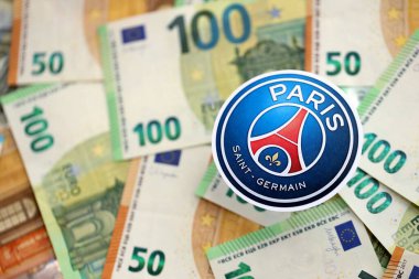 KYIV, UKRAINE - 23 Şubat 2025 Paris Saint Germain FC futbol kulübü rozeti büyük miktarda EURO para banknotları üzerinde yatıyor