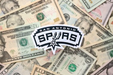 KYIV, UKRAINE - 23 Şubat 2025 San Antonio Spurs basketbol takımı rozeti Amerikan dolarlarının büyük miktarına yakın.