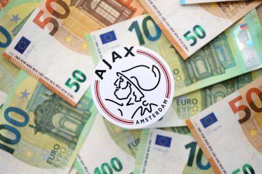 KYIV, UKRAINE - 23 Şubat 2025 AFC Ajax futbol kulübü rozeti büyük miktarda EURO para banknotlarında yatıyor