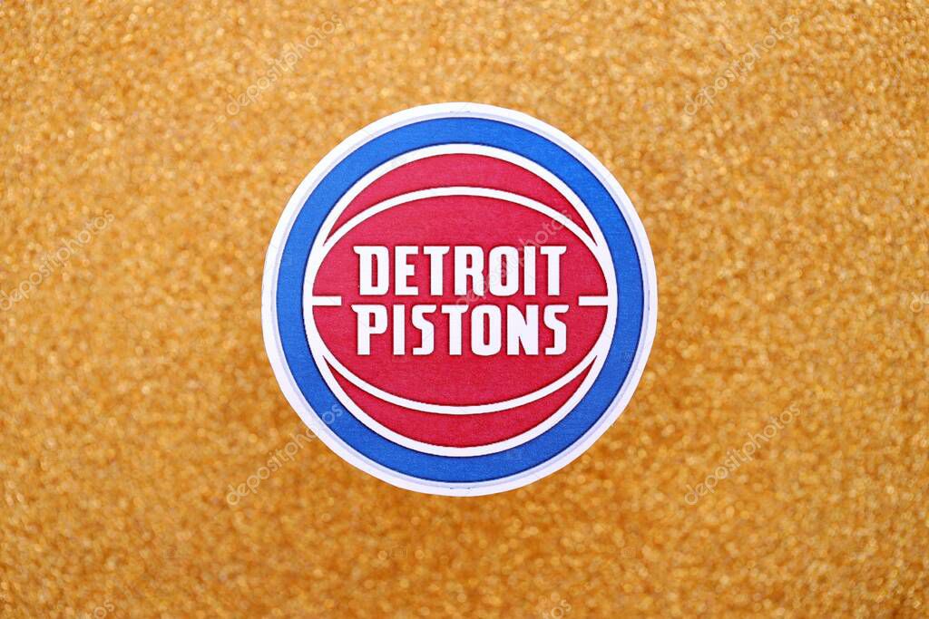 KYIV, UKRAINE - FEBRUARY 23, 2025 Detroit Pistons basketball team badge lies on golden yellow glitter background banner
