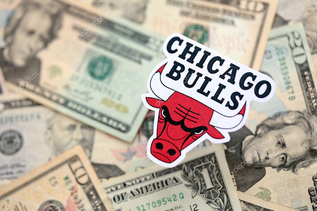 KYIV, UKRAINE - FEBRUARY 23, 2025 Chicago Bulls basketball team badge lies on big amount of US dollar bills close up