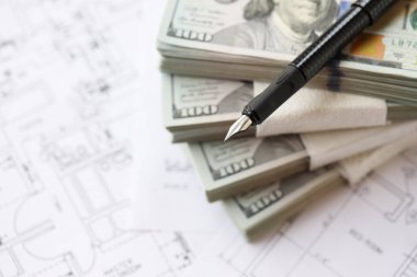 Kalemle birlikte yüklü miktarda Amerikan doları banknotları ve konut projesinin planları yakın plan. Yatırım ve inşaat projesi kavramı