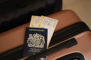 Biletli İngiliz pasaportu havaalanı bekleme salonundaki turistik bavulun üzerinde yatıyor. Dünya çapında seyahat ve uluslararası turizm kavramı