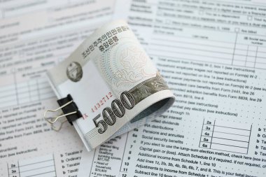 Kuzey Kore büyük miktarlarda para kazandı. Masada vergi formları var. Muhasebe ve vergilendirme kavramı