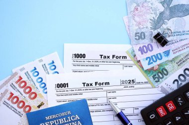 Arjantin Pezosu 'nun para faturaları kalem, hesap makinesi, pasaport ve vergi formlarıyla dolu. Finans ve bankacılık kavramı