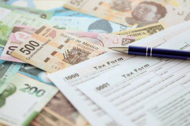 Değişik para birimlerinden ve ülkelerden oluşan büyük miktarlarda para ve vergi beyannamesi doldurulmaya hazır. Uluslararası nakitin çeşitli arka planında büyük bir yığın var.