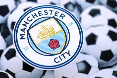 KYIV, UKRAINE - 23 Şubat 2025 Manchester FC futbol kulübü rozeti futbol toplarının arka plan pankartıyla yatar