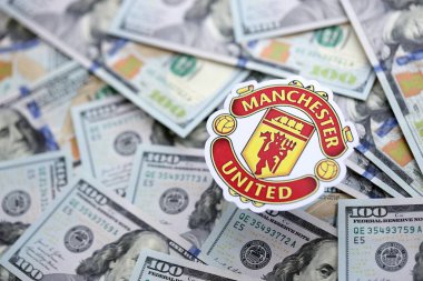 KYIV, UKRAINE - 23 Şubat 2025 Manchester United FC futbol kulübü rozeti büyük miktarlarda Amerikan doları üzerinde yer almaktadır.