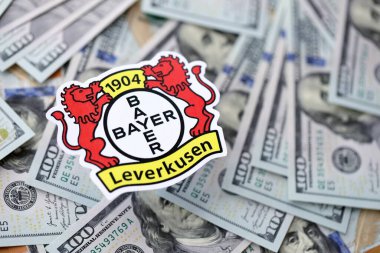 KYIV, UKRAINE - 23 Şubat 2025 Bayer 04 Leverkusen futbol kulübü rozeti yüzlük banknotların üzerinde yatıyor