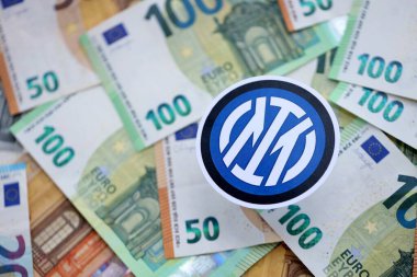KYIV, UKRAINE - 23 Şubat 2025 Inter Milan FC futbol kulübü rozeti büyük miktarda EURO para banknotları üzerinde yatıyor