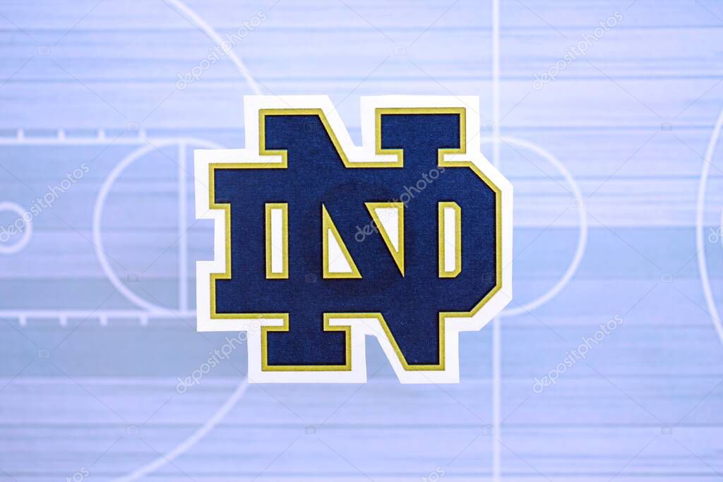 KYIV, UKRAINE - FEBRUARY 23, 2025 Notre Dame Fighting Irish basketball team badge lies on basketball stadium map background banner