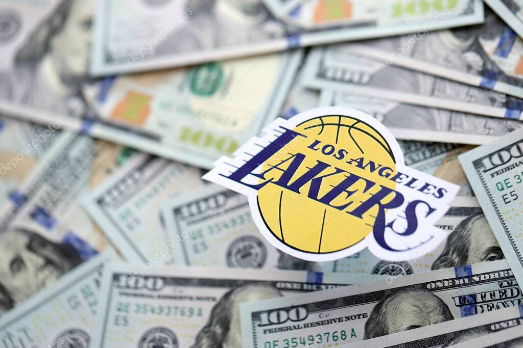 KYIV, UKRAINE - FEBRUARY 23, 2025 Los Angeles Lakers basketball team badge lies on big amount of hundred US dollar bills close up