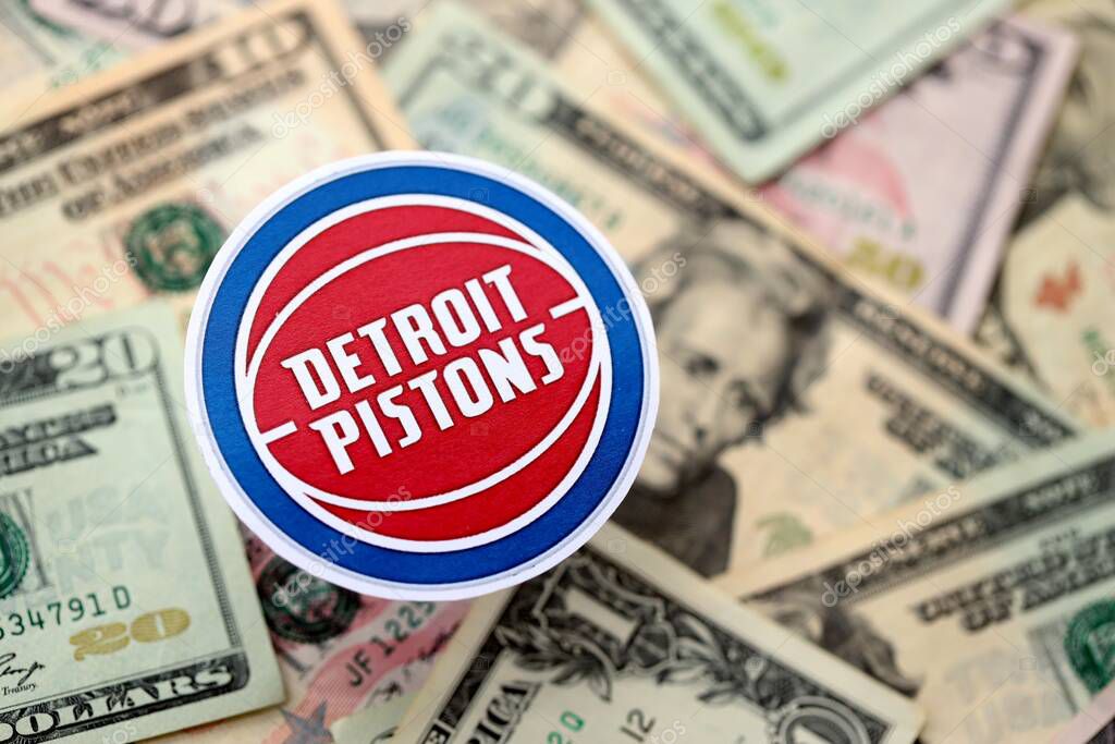 KYIV, UKRAINE - FEBRUARY 23, 2025 Detroit Pistons basketball team badge lies on big amount of US dollar bills close up