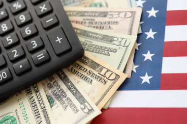 Amerikan doları para ve hesap makinesi Amerikan bayrağına yakın. Para yatırımı konsepti ve vergi ödeme