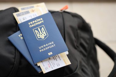 Siyah turistik sırt çantası üzerinde uçuş biletleri olan iki Ukrayna biyometrik pasaportu.