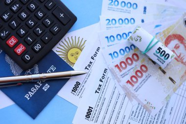 Arjantin Pezosu 'nun para faturaları kalem, hesap makinesi, pasaport ve vergi formlarıyla dolu. Finans ve bankacılık kavramı