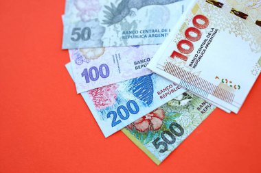 Arjantin pezosu büyük miktarlarda para kırmızı renkli masaya yakın duruyor. Finans ve bankacılık kavramı