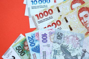 Arjantin pezosu büyük miktarlarda para kırmızı renkli masaya yakın duruyor. Finans ve bankacılık kavramı