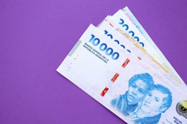 Arjantin pezosu büyük miktarda para mor renkli masaya yakın duruyor. Finans ve bankacılık kavramı