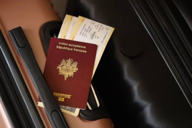 Biletli Fransız pasaportu havaalanı bekleme salonundaki turistik bavulun üzerinde yatıyor. Dünya çapında seyahat ve uluslararası turizm kavramı