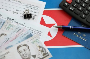 Kuzey Kore büyük miktarlarda para kazandı. Masada kalem, hesap makinesi, pasaport ve vergi formları var. Vergi ödeme ve muhasebe kavramı