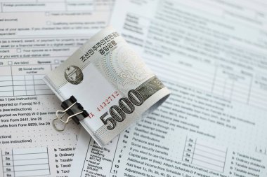 Kuzey Kore büyük miktarlarda para kazandı. Masada vergi formları var. Muhasebe ve vergilendirme kavramı