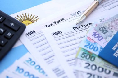 Arjantin Pezosu 'nun para faturaları kalem, hesap makinesi, pasaport ve vergi formlarıyla dolu. Finans ve bankacılık kavramı