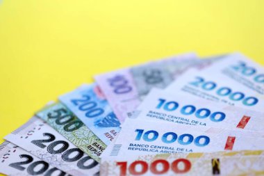 Arjantin pezosu büyük miktarlarda banknotlar sarı renkli masaya yakın duruyor. Finans ve bankacılık kavramı
