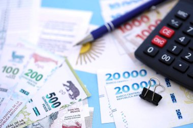 Arjantin Pezosu 'nun para faturaları kalem, hesap makinesi, pasaport ve vergi formlarıyla dolu. Finans ve bankacılık kavramı