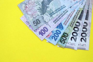 Arjantin pezosu büyük miktarlarda banknotlar sarı renkli masaya yakın duruyor. Finans ve bankacılık kavramı