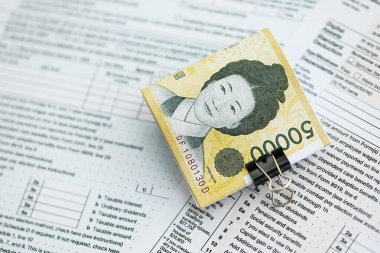 Güney Kore büyük miktarlarda para kazandı. Masada vergi formları var. Muhasebe ve vergilendirme kavramı