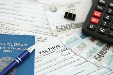 Kuzey Kore büyük miktarlarda para kazandı. Masada kalem, hesap makinesi, pasaport ve vergi formları var. Vergi ödeme ve muhasebe kavramı