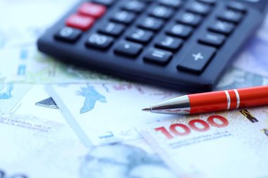 Arjantin Pezosu 'nun büyük miktarlarda para banknotları kalem ve hesap makinesiyle masanın üzerinde duruyor. Maliye ve vergi ödeme kavramı