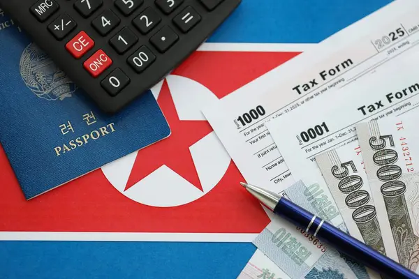 Kuzey Kore büyük miktarlarda para kazandı. Masada kalem, hesap makinesi, pasaport ve vergi formları var. Vergi ödeme ve muhasebe kavramı