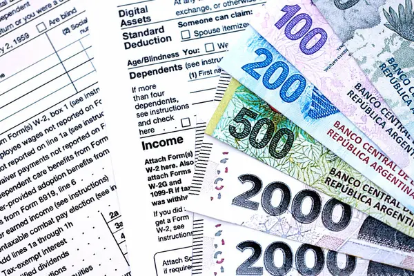 Arjantin pezosu. Büyük miktarda para. Masada, kalem ve vergi formları var.